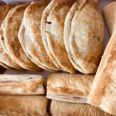 Six golden baked pasties and six flaky sausage rolls.