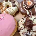 Four assorted doughnuts with colourful toppings and fillings.